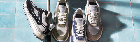 Four retro-style athletic Floris van Bommel sneakers arranged on a glossy blue tiled floor, showing different colourways including black and white, beige and gray, and blue and white.