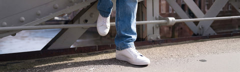 White Floris van Bommel sneakers worn with blue jeans.