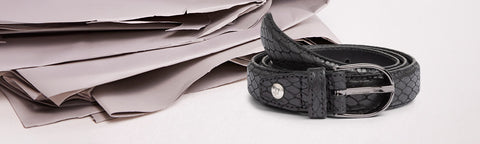 Black leather belt brand Floris van Bommel on a stack of newspapers