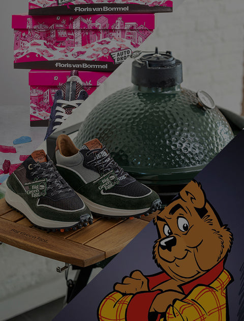 A pair of dark grey and green athletic sneakers displayed on a wooden table next to a green ceramic kamado grill, with Floris van Bommel-branded and autodrop pink shoe boxes stacked in the background and a cartoon bear graphic in the bottom right corner.