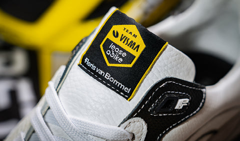 Visma sneaker Floris van Bommel. Close-up of a white leather sneaker with black overlays and a yellow-and-black tongue label