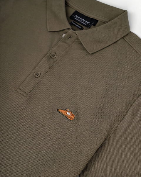 Floris van Bommel. Close-up of a folded olive green polo shirt showing the collar, two-button placket, and a small embroidered chest logo.